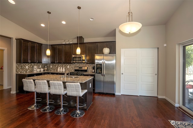 kitchen featuring decorative light fixtures, tasteful backsplash, an island with sink, and stainless steel appliances