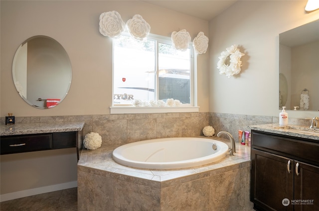 bathroom featuring tiled tub, vanity, and tile patterned flooring