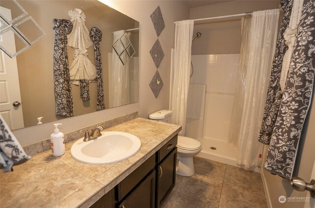 bathroom with curtained shower, tile patterned floors, toilet, and vanity