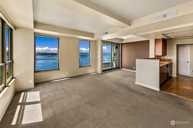 unfurnished living room featuring a water view and dark colored carpet