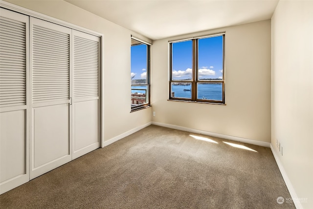 unfurnished bedroom featuring a water view and carpet