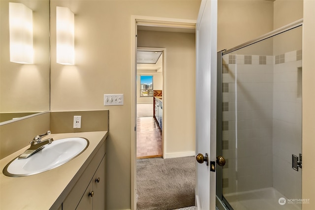 bathroom with a shower with shower door and vanity