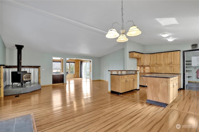 kitchen featuring decorative light fixtures, light wood-type flooring, vaulted ceiling, and light brown cabinets