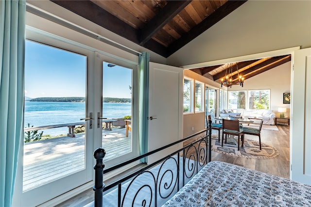 sunroom with a water view, lofted ceiling with beams, wooden ceiling, french doors, and a chandelier