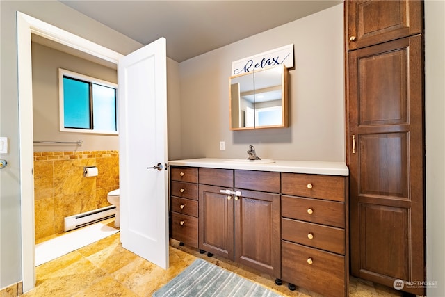 bathroom with vanity, tile walls, baseboard heating, and toilet