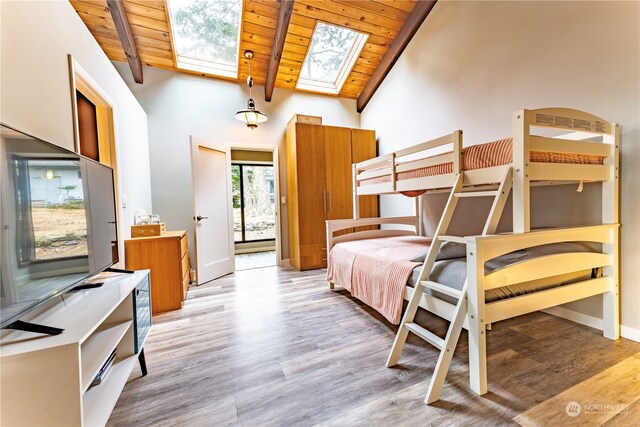 bedroom featuring wood ceiling, light hardwood / wood-style flooring, beam ceiling, a skylight, and high vaulted ceiling