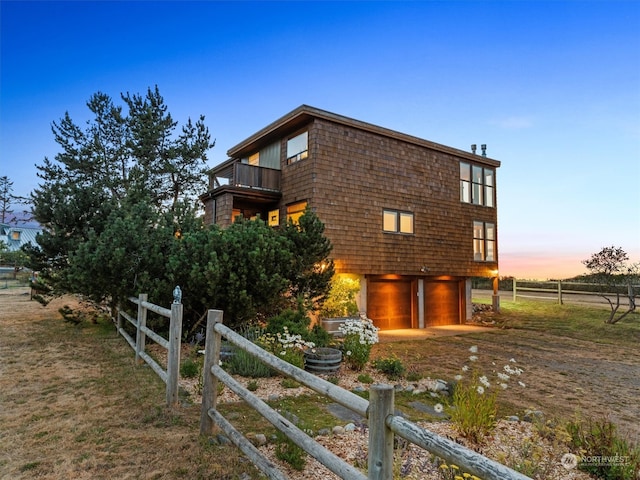 property exterior at dusk with a garage and a balcony