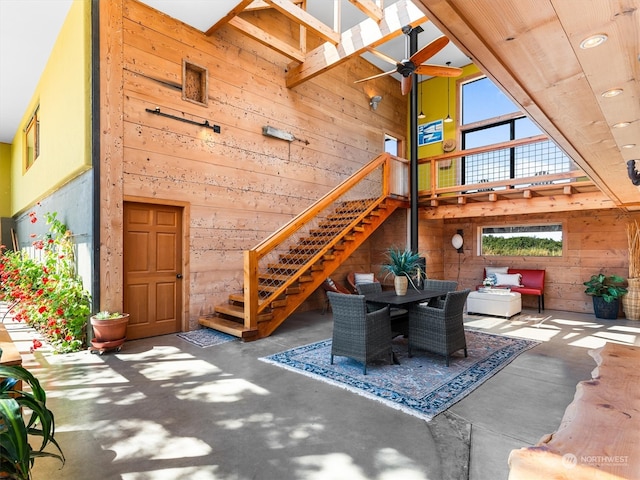 exterior space featuring ceiling fan, wood walls, and concrete floors