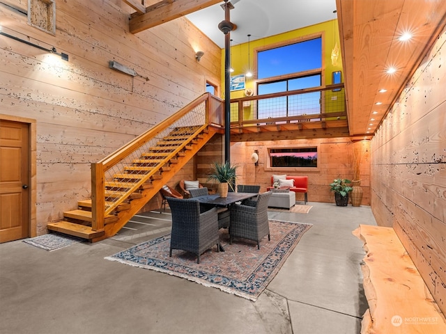 living room featuring wooden walls, concrete floors, and a high ceiling