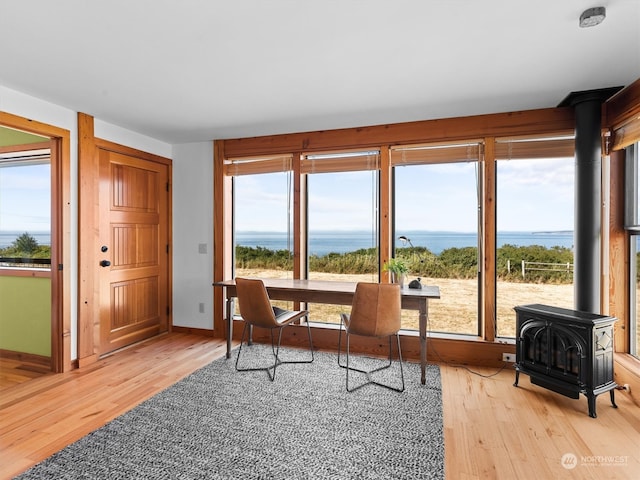 office area with a wood stove, light wood-type flooring, and a water view