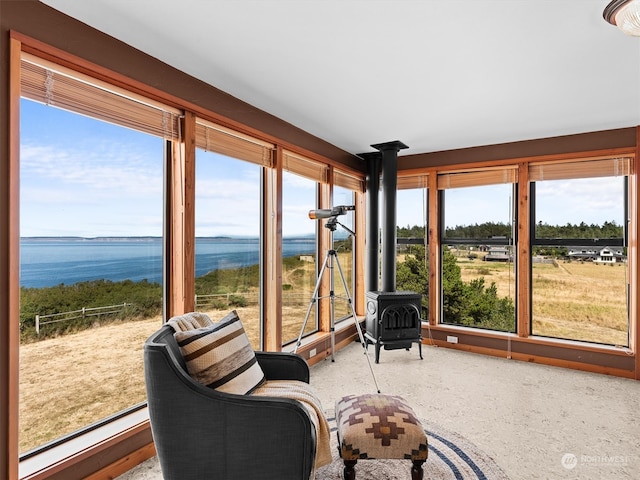 sunroom featuring a wood stove and a water view