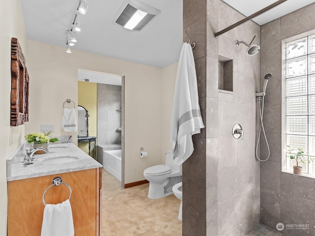 full bathroom featuring toilet, vanity, tiled shower / bath combo, track lighting, and a bidet