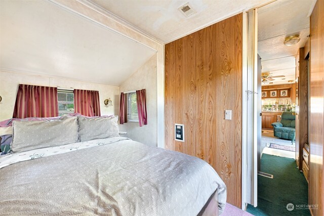 bedroom with wood walls, carpet floors, and lofted ceiling