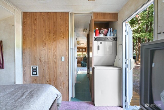 carpeted bedroom with wooden walls and stacked washing maching and dryer