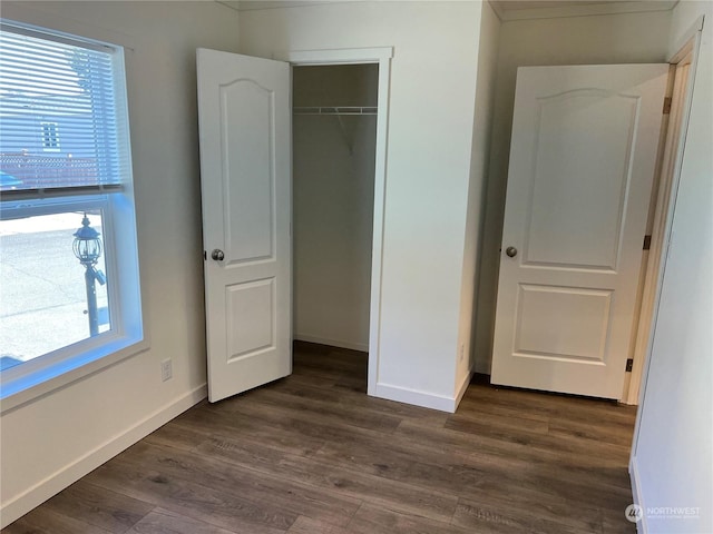 unfurnished bedroom with multiple windows, dark hardwood / wood-style flooring, and a closet