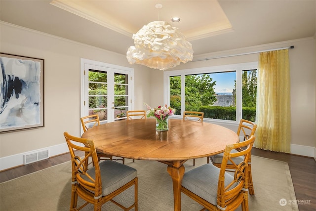 dining room featuring hardwood / wood-style floors, ornamental molding, a notable chandelier, a tray ceiling, and french doors