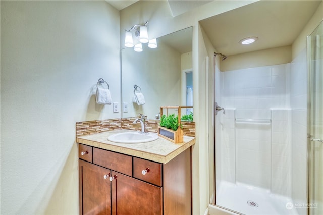 bathroom with vanity, a shower with shower door, and tasteful backsplash