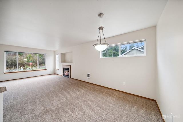 unfurnished living room featuring a tile fireplace, a healthy amount of sunlight, and carpet