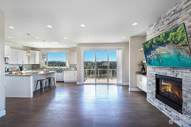 kitchen featuring white cabinetry, dishwasher, dark hardwood / wood-style flooring, a fireplace, and a kitchen breakfast bar