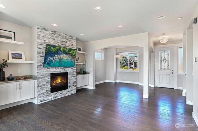 unfurnished living room featuring a stone fireplace and dark hardwood / wood-style flooring