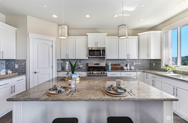 kitchen with a center island, decorative backsplash, white cabinets, and stainless steel appliances