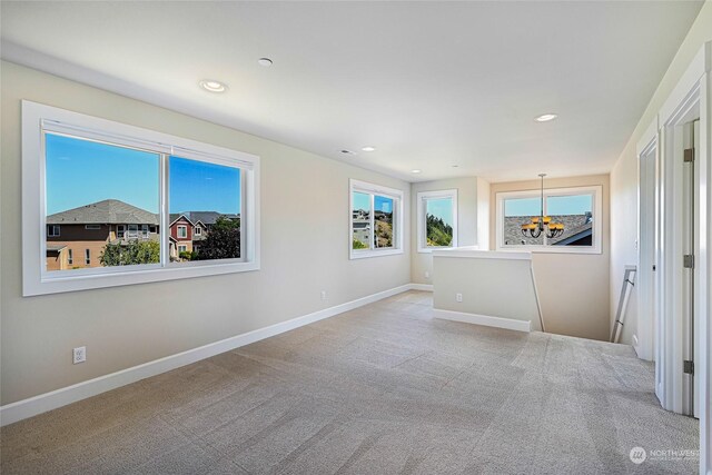 unfurnished room featuring a notable chandelier and light carpet