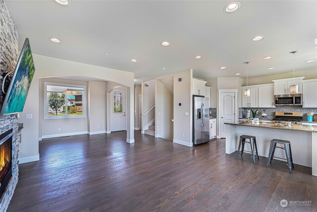 kitchen featuring a stone fireplace, stainless steel appliances, dark hardwood / wood-style floors, and white cabinets