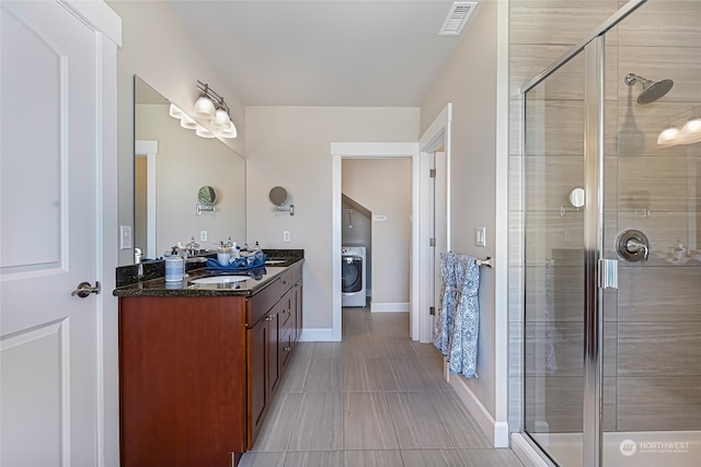 bathroom featuring a shower with shower door, washer / dryer, tile patterned flooring, and double vanity