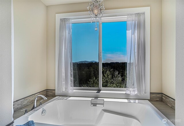 bathroom with a notable chandelier and a bathtub