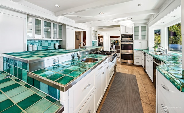 kitchen with white cabinetry, sink, decorative backsplash, appliances with stainless steel finishes, and beam ceiling