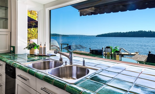 kitchen with a water view, white cabinetry, and sink