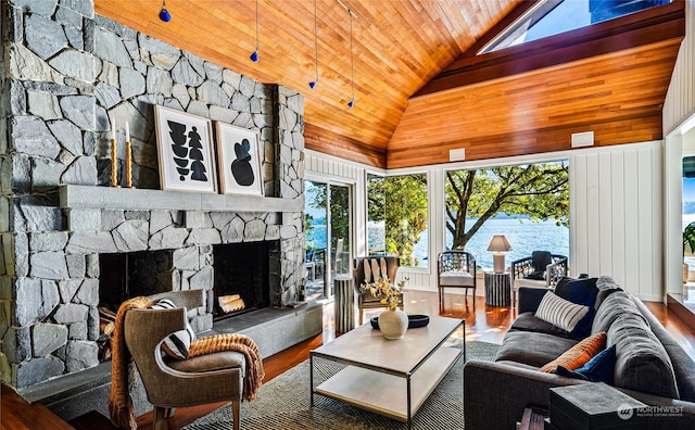 living room featuring a wealth of natural light, hardwood / wood-style floors, a stone fireplace, and wooden ceiling