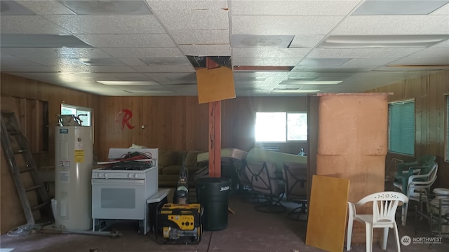 basement with a paneled ceiling and water heater