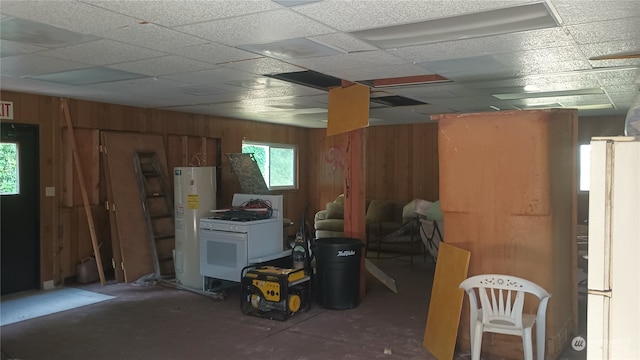 basement with a paneled ceiling, white fridge, and water heater