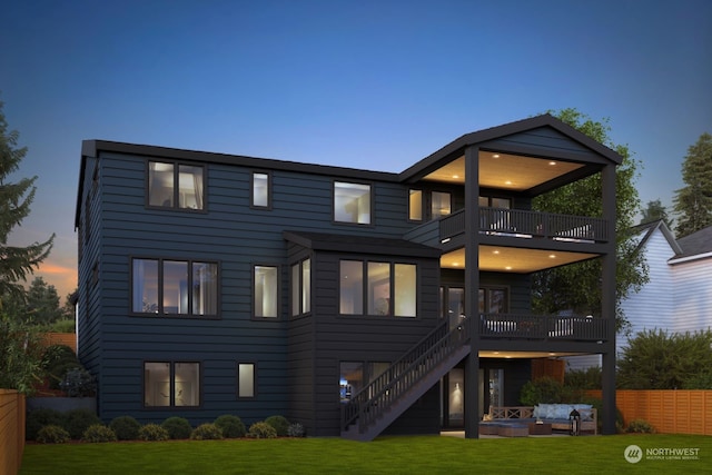 back house at dusk featuring an outdoor hangout area, a patio, a balcony, and a yard