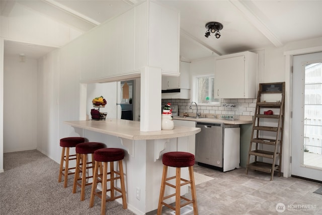 kitchen with dishwasher, a breakfast bar, light countertops, a healthy amount of sunlight, and backsplash