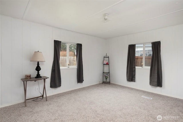 spare room with a healthy amount of sunlight, carpet flooring, and visible vents