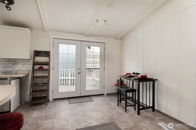 doorway with french doors, a notable chandelier, and lofted ceiling with beams