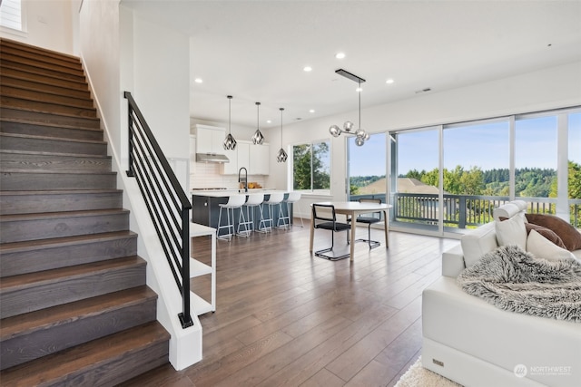 living room featuring a notable chandelier, sink, and dark hardwood / wood-style flooring