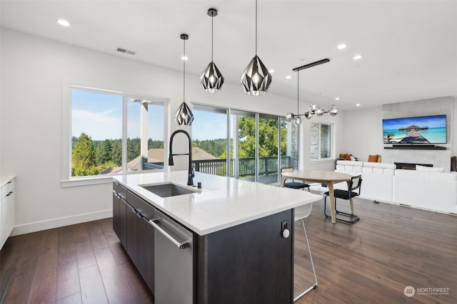 kitchen with pendant lighting, sink, dishwasher, a center island with sink, and dark wood-type flooring