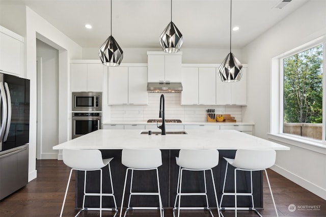 kitchen featuring appliances with stainless steel finishes, dark hardwood / wood-style flooring, white cabinets, and backsplash