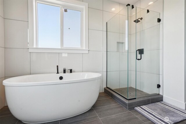 bathroom featuring plus walk in shower, tile patterned flooring, and tile walls