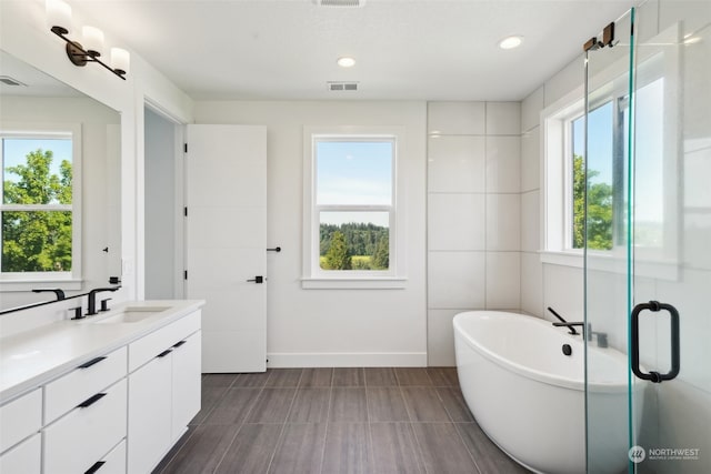 bathroom featuring vanity, tile walls, a bathing tub, and tile patterned floors