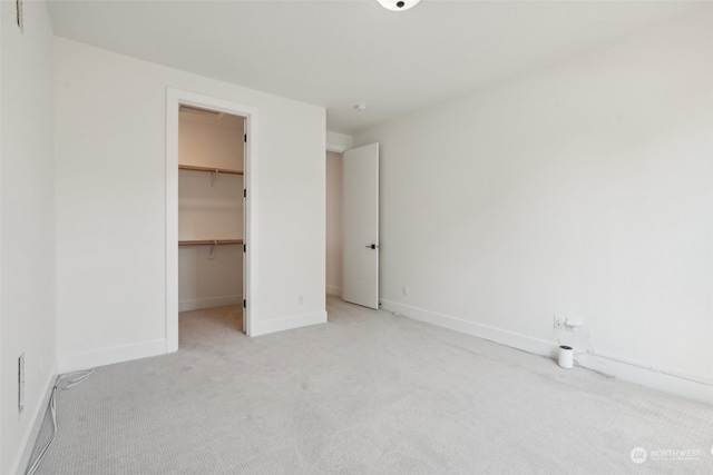 unfurnished bedroom with light carpet, a closet, and a walk in closet