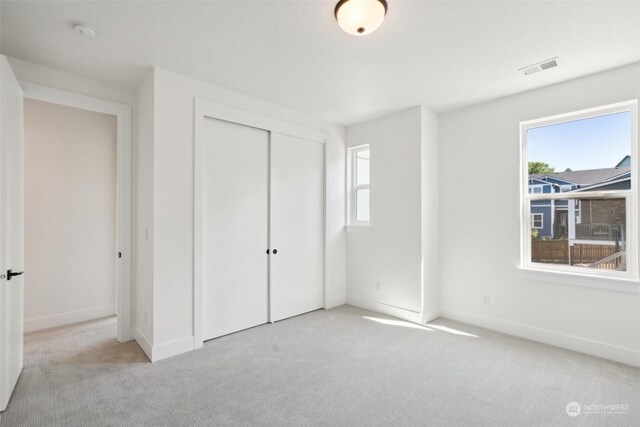 unfurnished bedroom featuring light carpet and a closet