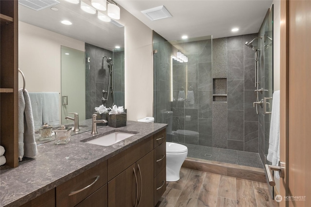 bathroom with vanity, hardwood / wood-style flooring, a shower with shower door, and toilet