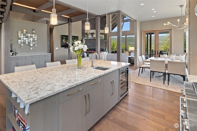 kitchen with gray cabinetry, sink, pendant lighting, and a center island with sink