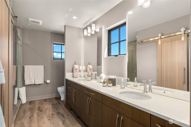 bathroom featuring vanity, hardwood / wood-style flooring, toilet, and a healthy amount of sunlight