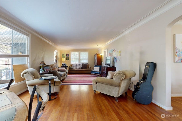 living room with baseboards, ornamental molding, arched walkways, and wood finished floors