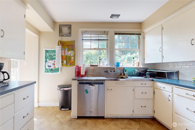 kitchen with light tile patterned floors, a sink, white cabinetry, stainless steel dishwasher, and tasteful backsplash